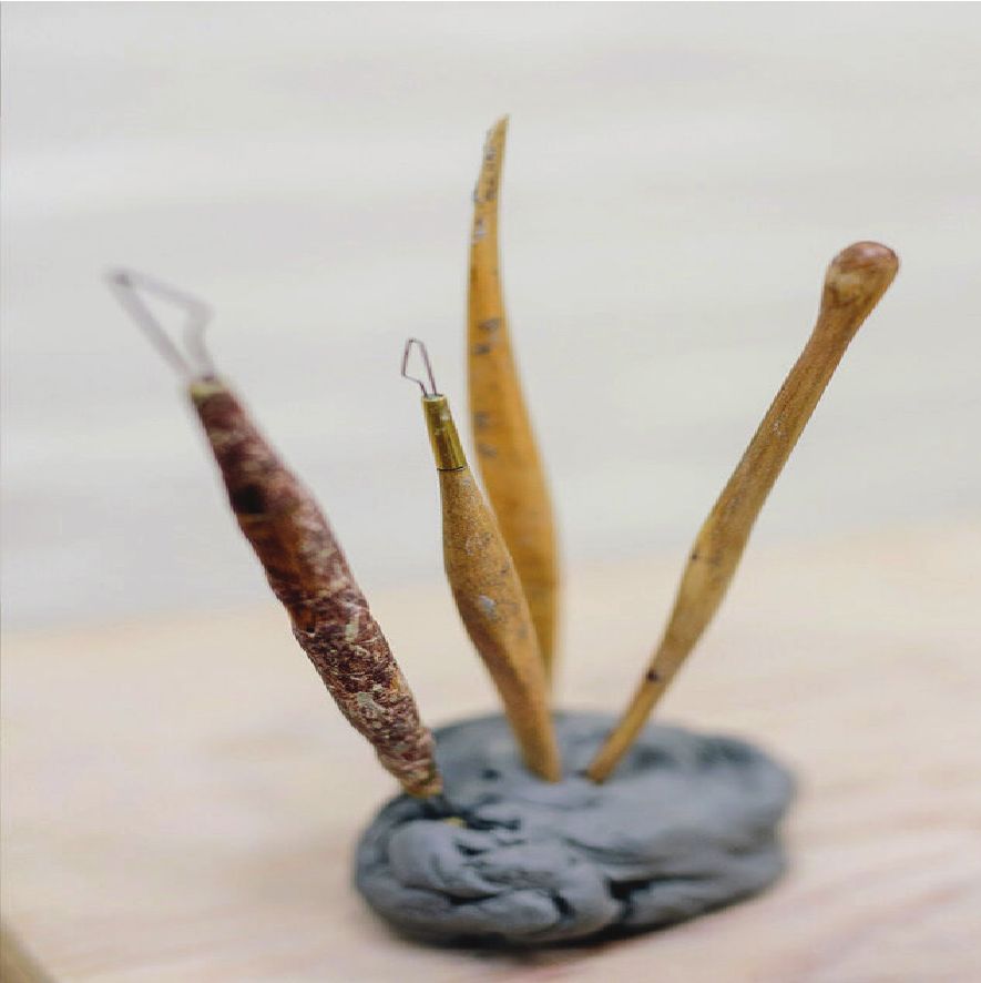 Wooden sculpting tools standing in a lump of grey clay